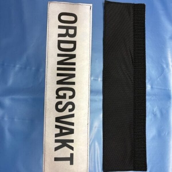 ORDNINGSVAKT märke med svart text på reflexbakgrund.