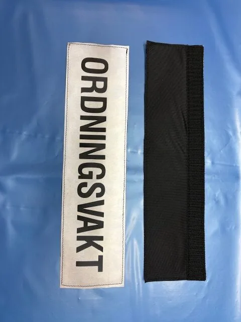 ORDNINGSVAKT märke med svart text på reflexbakgrund.